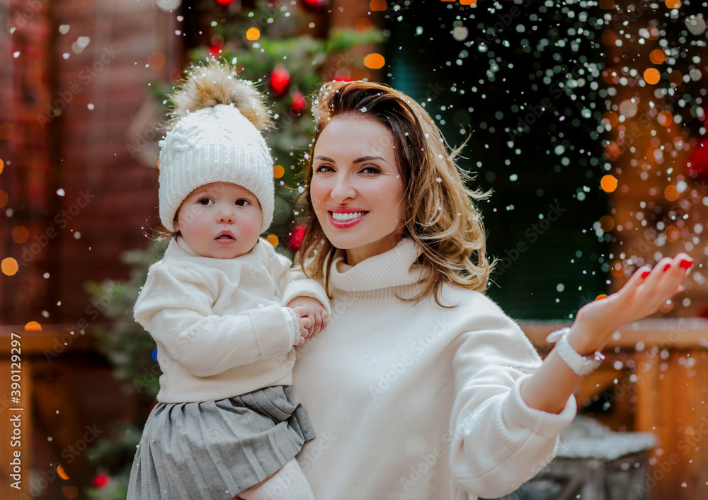 Woman posing with her baby girl in the back yard with Christmas background.Snow Woman posing with her baby girl in the back yard with Christmas background.Snow