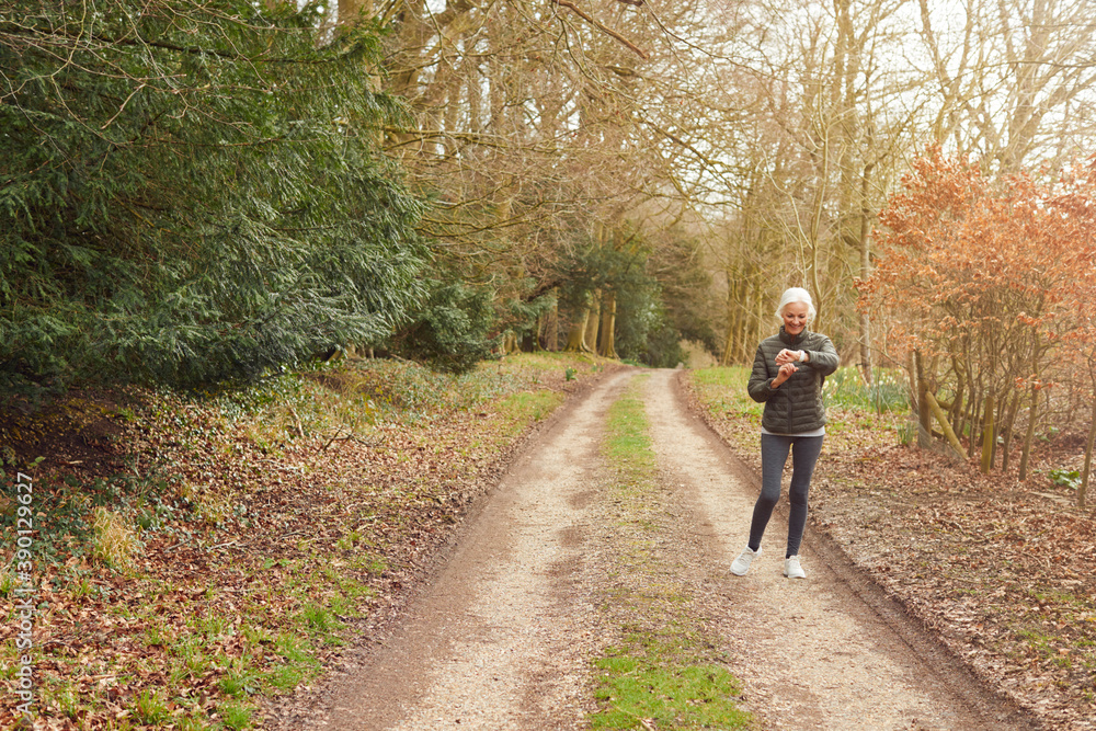 Senior Woman Running In Autumn Countryside Exercising Checking Smart Watch Fitness Activity App Senior Woman Running In Autumn Countryside Exercising Checking Smart Watch Fitness Activity App