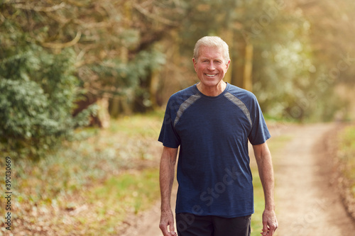Fototapeta Naklejka Na Ścianę i Meble -  Portrait Of Smiling Senior Man Running In Autumn Countryside Exercising During Covid 19 Lockdown