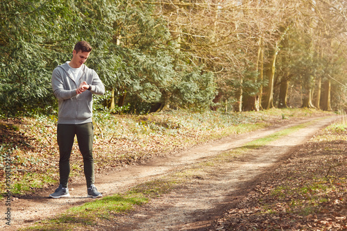 Man Running In Countryside Exercising Checking Smart Watch Fitness Activity App