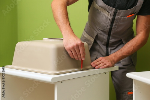hands of worker installs kitchen sink