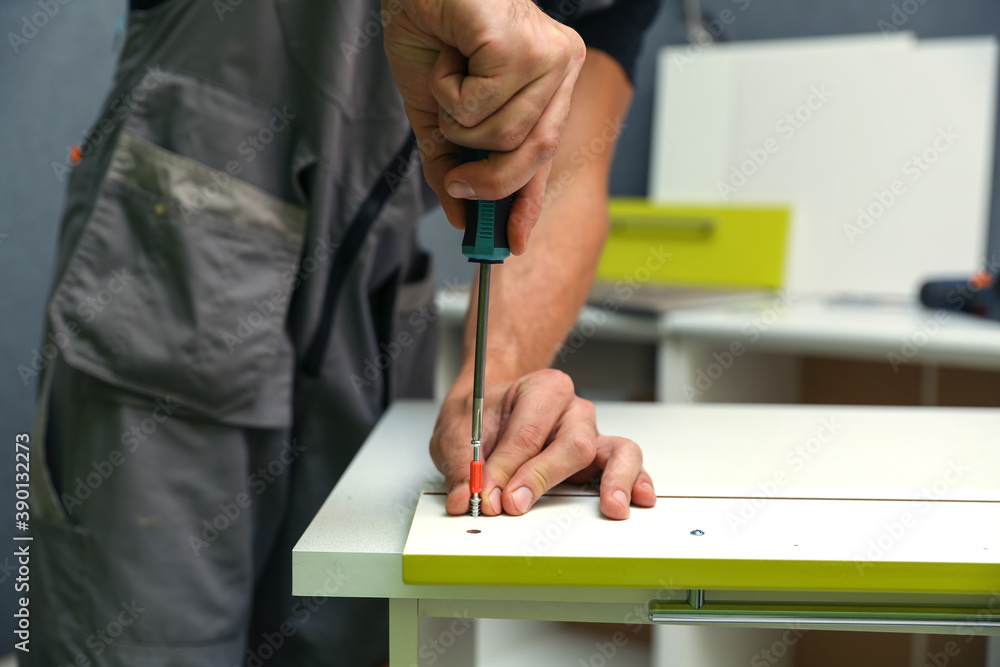 worker assembles furniture in the kitchen. furniture assembly service concept