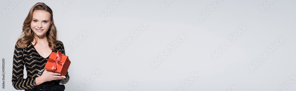 cheerful woman holding christmas present isolated on grey, banner cheerful woman holding christmas present isolated on grey, banner