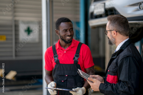 Fotografija The mechanic discuss with his chief during car damage inspection at the garage