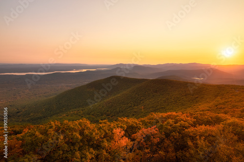 Warm golden sunlight shining across layers of rolling mountains during sunset. Overlook Mountain, New York. 