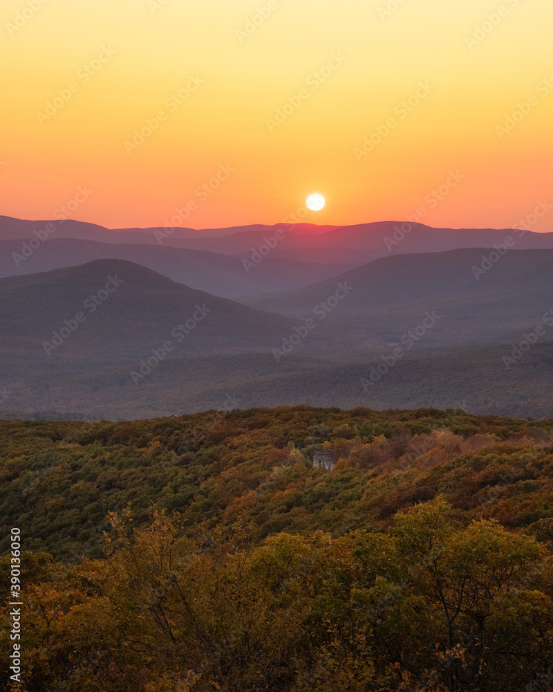 Warm golden sunlight shining across layers of rolling mountains during sunset. Overlook Mountain, New York. 