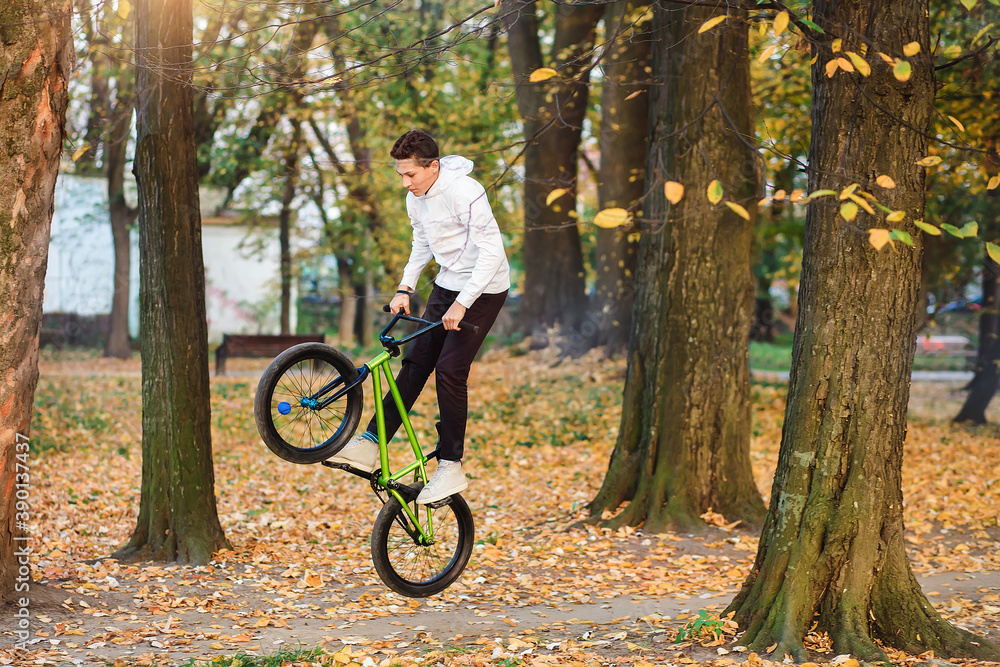 Park , a teenager boy jumps high on a bicycle. Extreme sport.