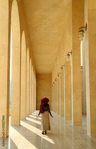 Vertical image of a female visitor walking in the marble corridor