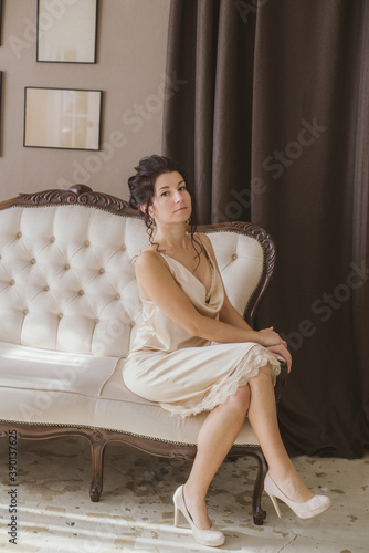 Lovely and elegant girl with dark hair, in beautiful fashionable dress with hairstyles in a classic light interior . Beauty and fashion. 