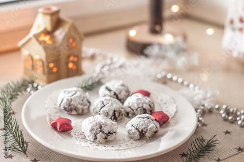 Plate with chocolate cakes on an openwork napkin, surrounded by decor. photo