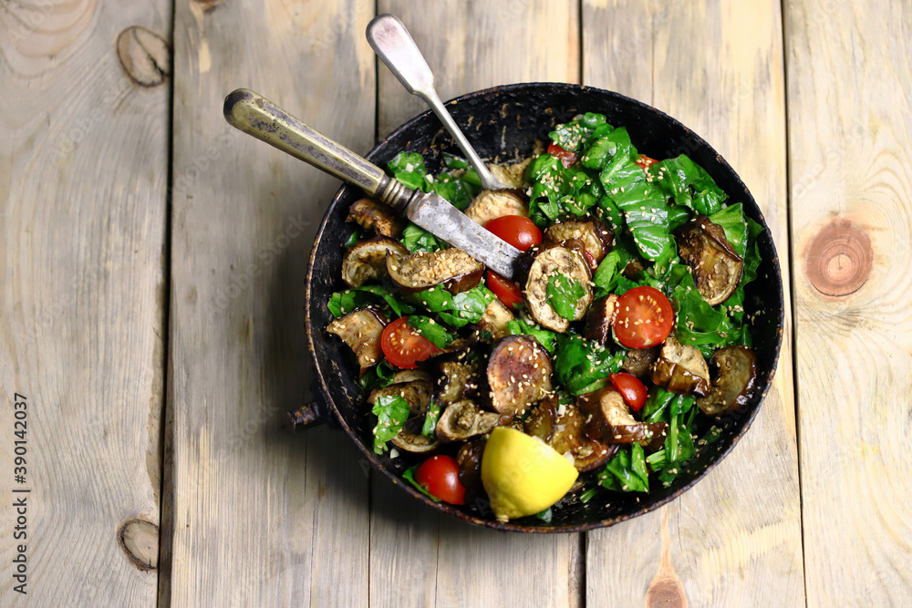 Selective focus. Warm salad with spinach and eggplant in a frying pan. Healthly food. Vegan lunch idea.