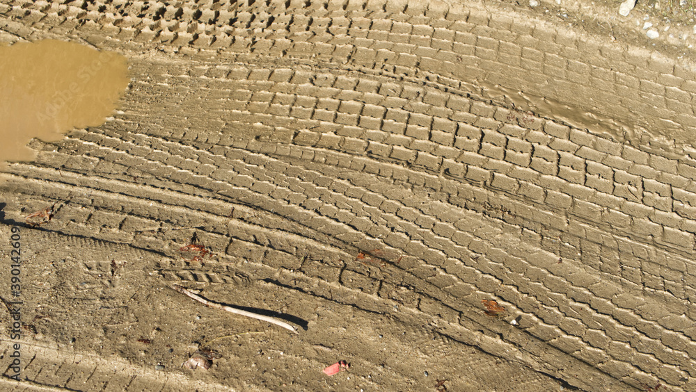 Fototapeta premium Muddy road with tyre tracks different tread patterns. Muddy wet track near a farm