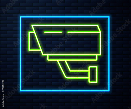 Glowing neon line Security camera icon isolated on brick wall background. Vector.