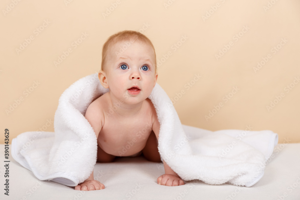 Child looking out under white towel. Pretty infant smiling happily Child looking out under white towel. Pretty infant smiling happily