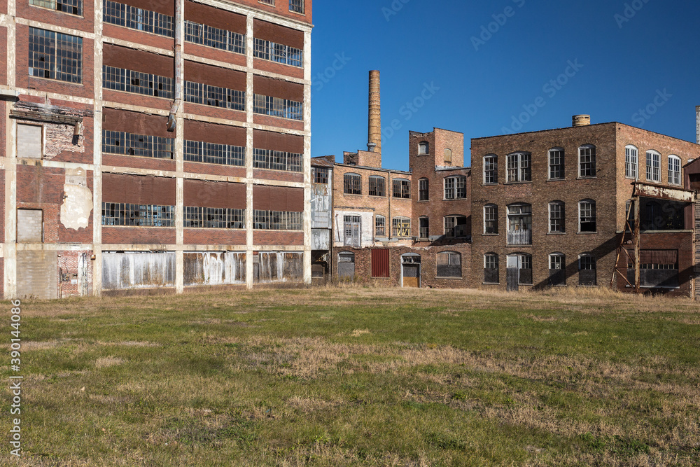 Open field in front of abandoned factory buildings with clear blue sky Open field in front of abandoned factory buildings with clear blue sky