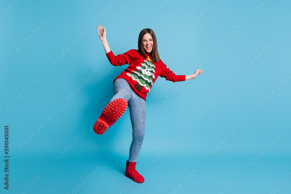 Full length body size photo of funny demale student playing fooling standing on one leg laughing showing red shoe wearing xmas sweater isolated on blue color background