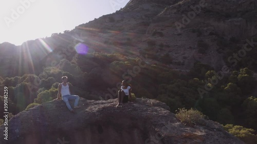 Tourist Couple Sitting In Sunlit Rocky Landscape