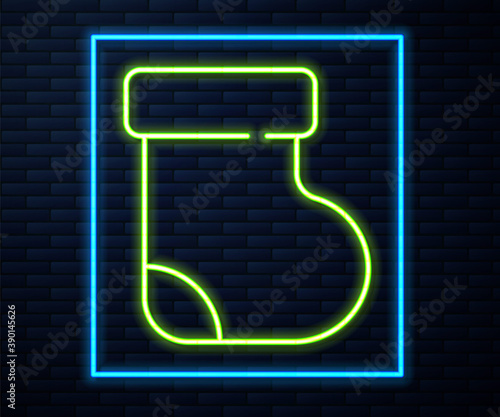 Glowing neon line Baby socks clothes icon isolated on brick wall background. Vector.