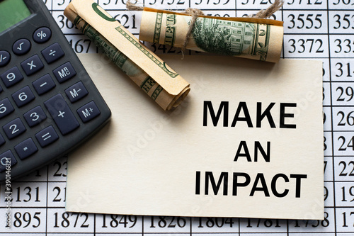 MAKE AN IMPACT word on a white sheet against a table with numbers, banknotes and calculator photo