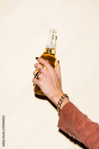cropped view of woman holding bottle with beer on white