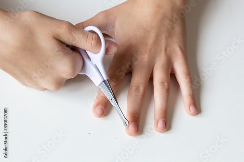  Child cuts his fingernails with scissors on a white background. Close-up.