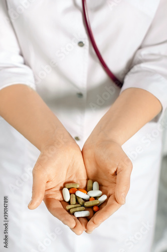 woman in white coat holding a handful of pills in palms