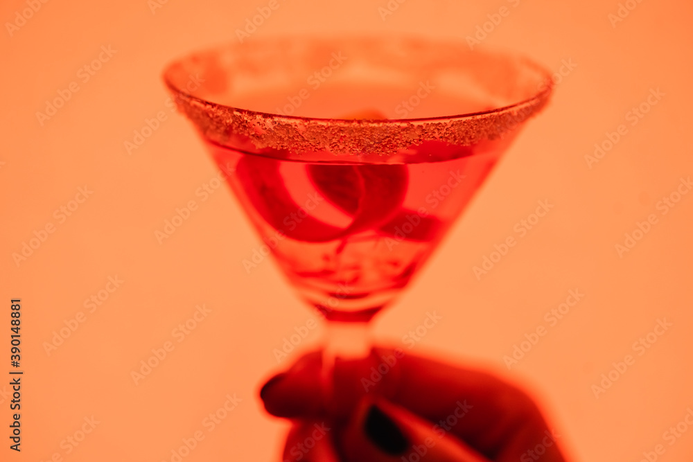Φωτογραφία close up of margarita cocktail with ice cubes and salt in female hand on orange