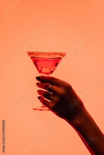 Sticker partial view of young woman holding margarita cocktail with ice cubes on orange