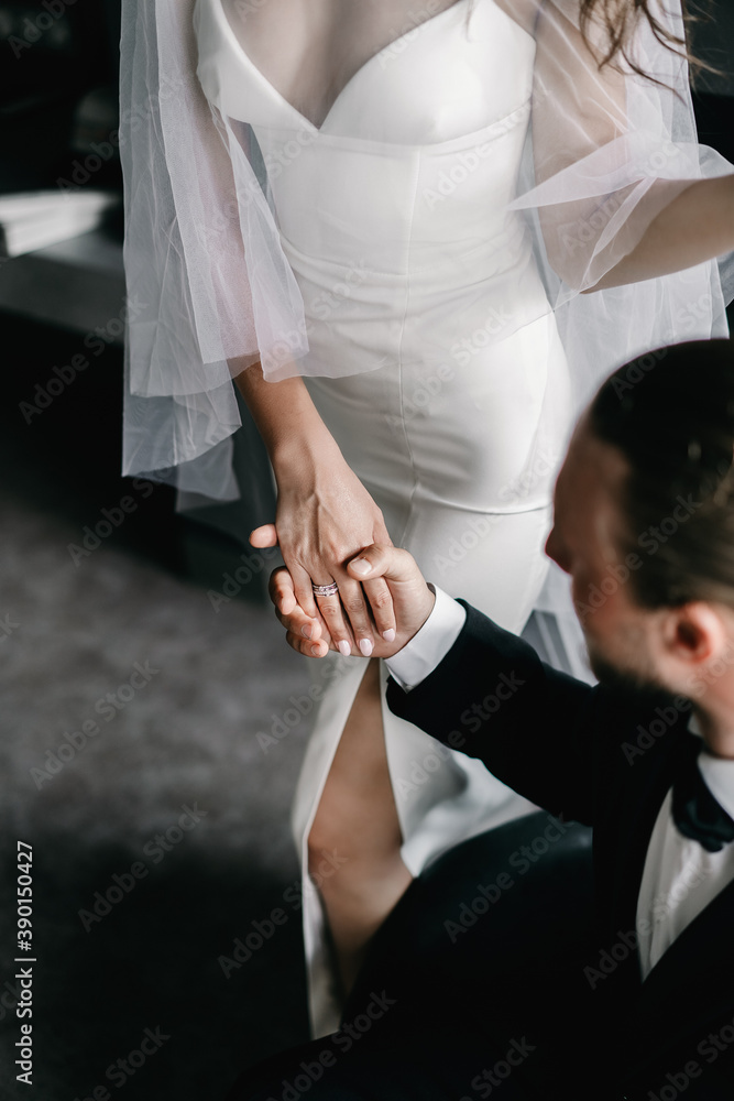 The groom in a suit holds the hand of the bride in a wedding dress The groom in a suit holds the hand of the bride in a wedding dress