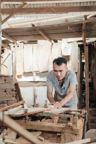 Asian workers use traditional dowels to smooth the surfaces of wooden planks in workshops