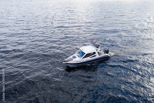 Aerial view fisherman on boat at the ocean. Top view beautiful seascape with the fishing boat. Aerial view fishing motor boat with angler. Ocean sea water wave reflections. Motor boat in the ocean. © Aleksei
