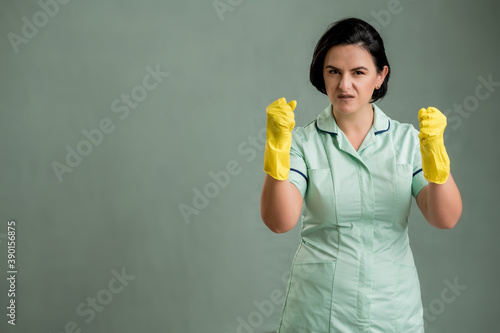 Young cleaning woman wearing a green shirt and yellow gloves showing fists © Cipri Suciu 