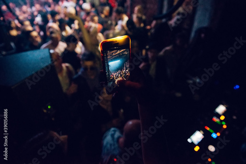 Woman holding smartphone and taking a video in nightclub