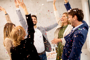 Group of business people celebrating and toasting with confetti falling in the office