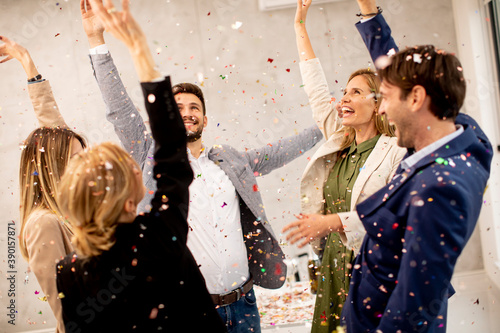 Fototapeta Group of business people celebrating and toasting with confetti falling in the o