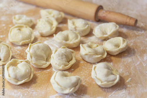 Closeup on semi-finished pelmeni dumplings on the wooden board.