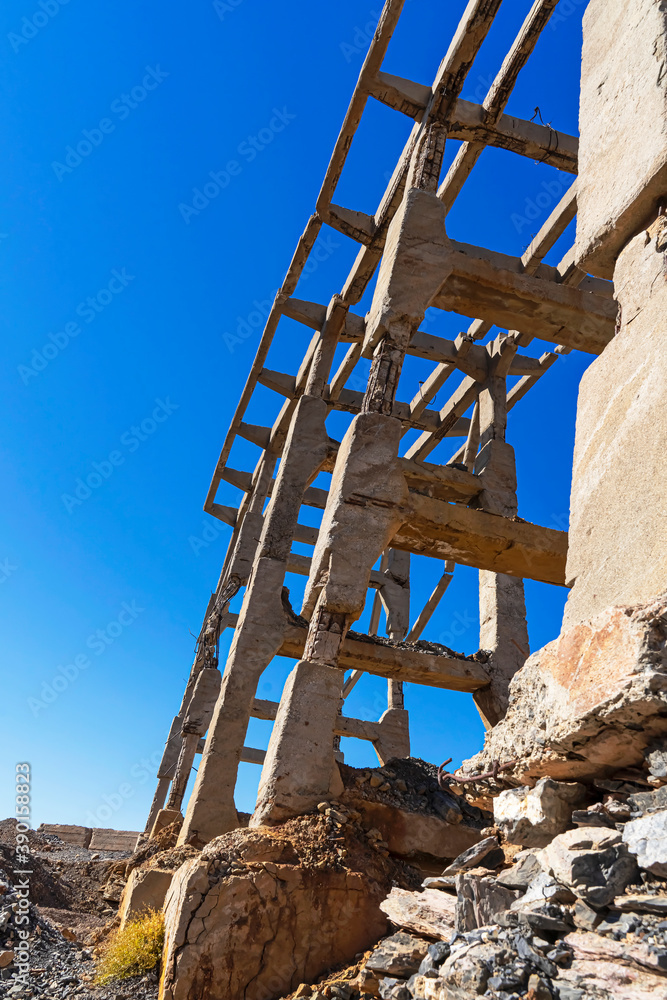 Fototapeta premium Old industrial bridge in the mountains. Destroyed mountain bridge. Abandoned concrete bridge. Concrete piles. Karatau mountains. Mountain stones. Blue sky. Mining Industrial Plant Bridge