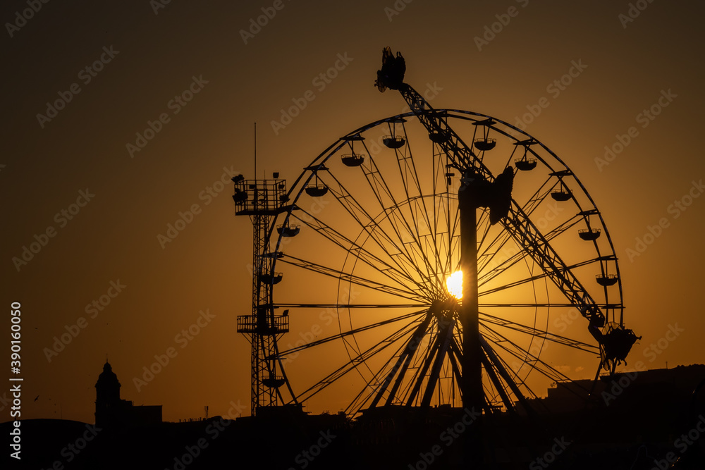 Ferris wheel in amusement park at sunset.
