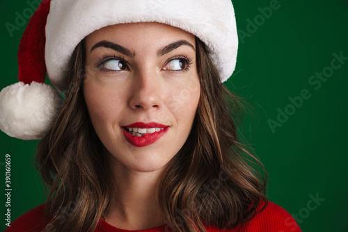 Beautiful thinking girl in Santa Claus hat posing and looking aside