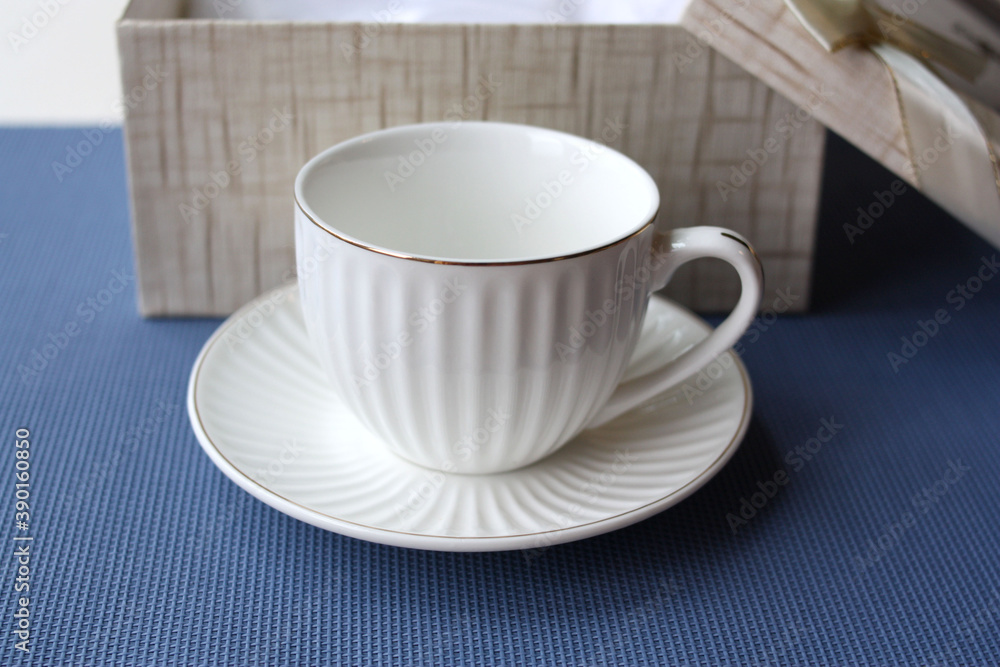 white coffee cup and saucer on the background of a gift box. white coffee cup and saucer on the background of a gift box.