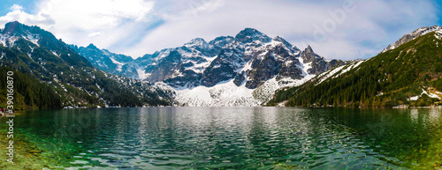 High rocky mountains and crystal clear turquoise lake high resolution panorama. Tatra National Park, a lake in the mountains covered with snow.