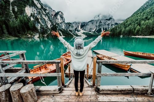 Happy woman travel lake of Braies, Italy - Girl with arms outstretched enjoying nature.