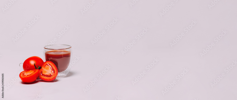 a glass of tomato juice and tomatoes on a white background