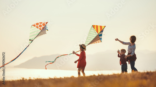 Happy family  mother and kids  launch  kite on nature at sunset. photo