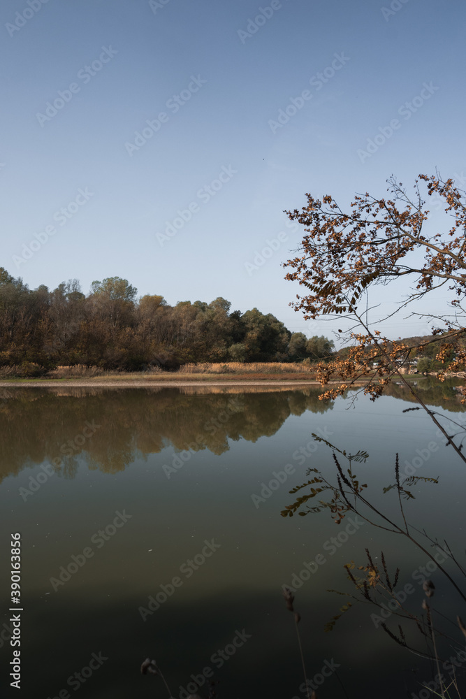 Lake in the Park, warm autumn time. Beautiful autumn landscape. Reflection of trees in the river, clear wide river in the forest. Lake in the Park, warm autumn time. Beautiful autumn landscape. Reflection of trees in the river, clear wide river in the forest.