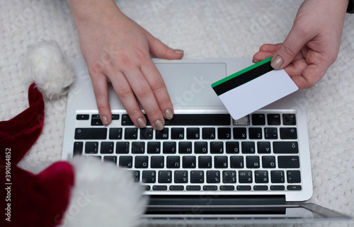 A woman orders gifts over the Internet. A woman's hand holds a credit card. Online ordering. Online shopping