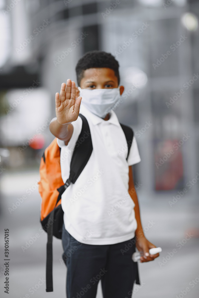 African boy holds antiseptick. Child in a summer city. Coronavirus theme.