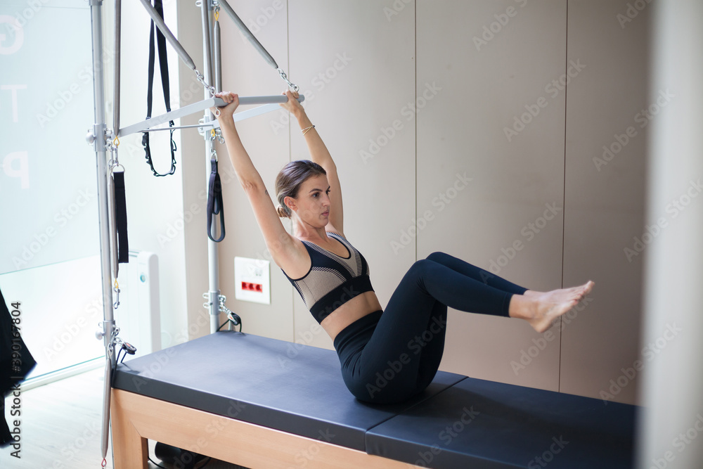 Attractive woman practicing pilates in reformer bed