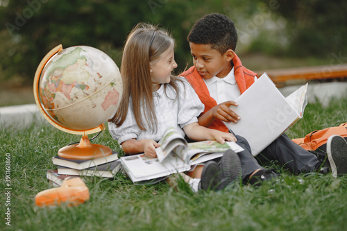 Mixed-races boy and little girl. Junior students in front of school. Pretty Caucasian girl. African American cute boy in white t-shirt. Pupils concept