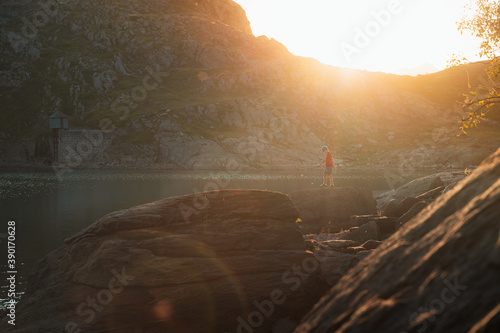 Kid walking on top of a rock during sunset in a lake